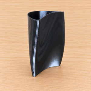 Vaso Vela nero in PETG su legno chiaro, ambientazione elaborata dalla fotografia reale